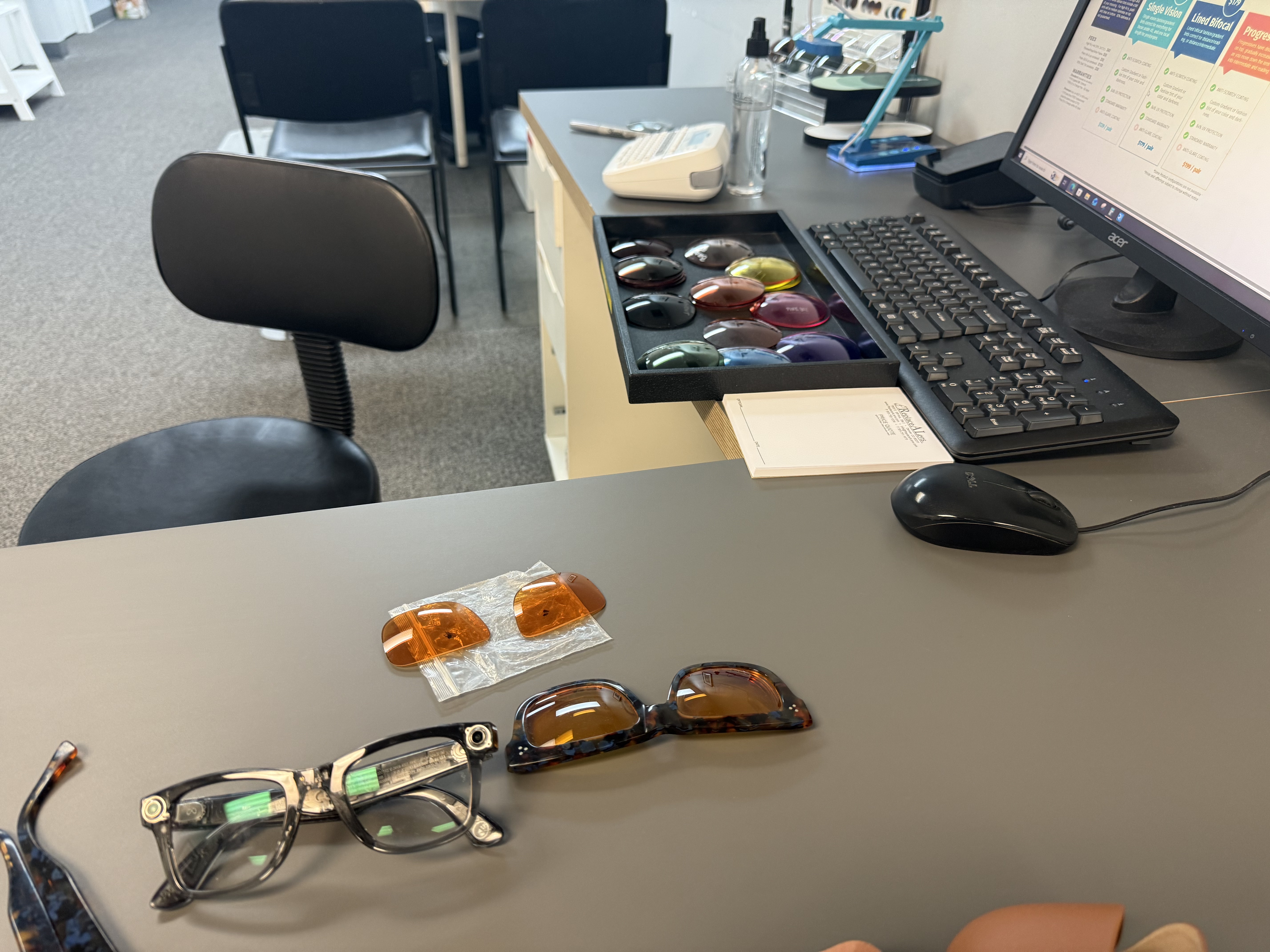 An optician's desk with Meta AI glasses and repaired sunglasses laid out alongside amber replacement lenses, a tray of colorful lens options in the background, Denver, Colorado.