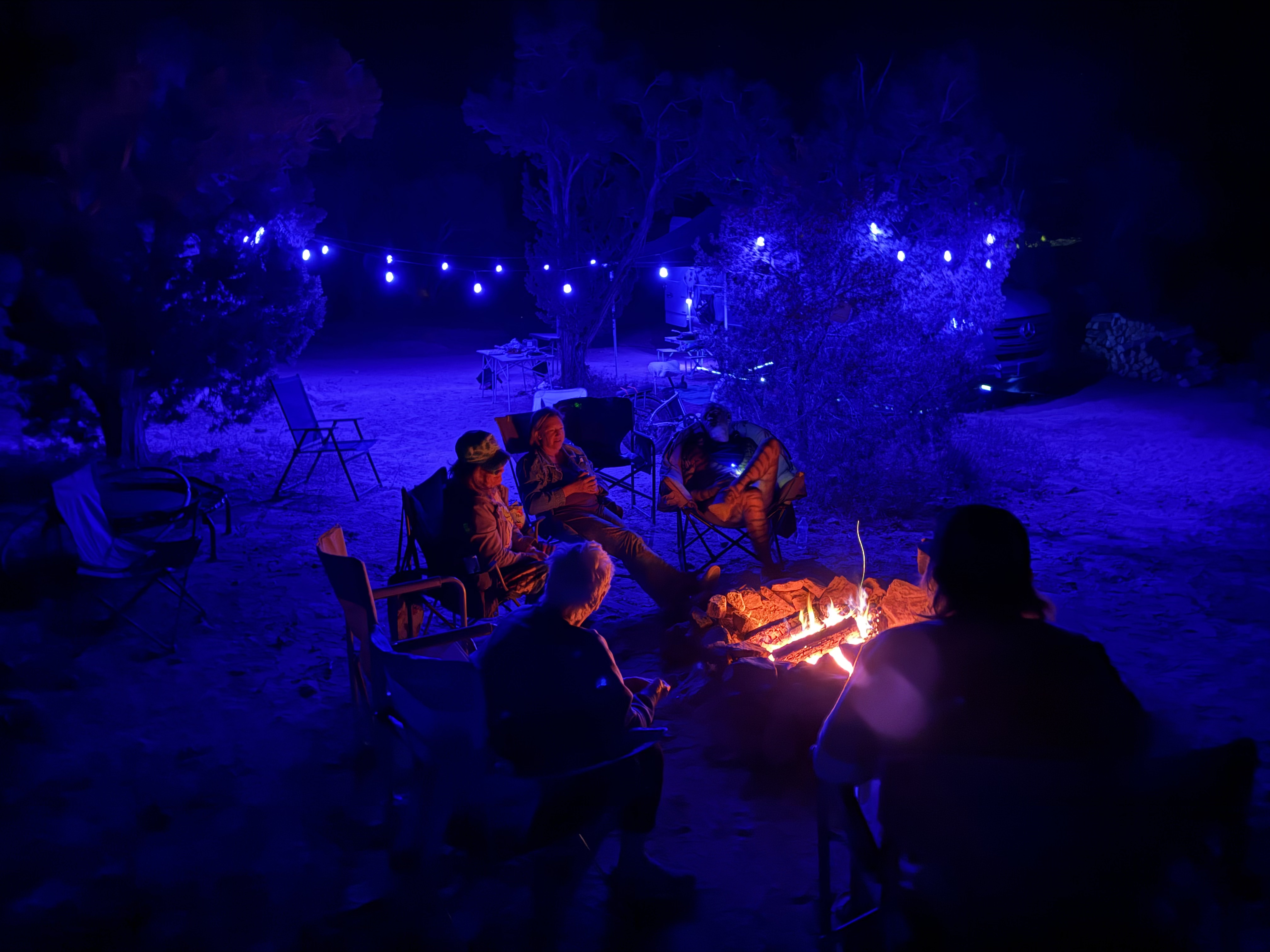 Campfire circle under blue string lights at night, Southern Utah desert