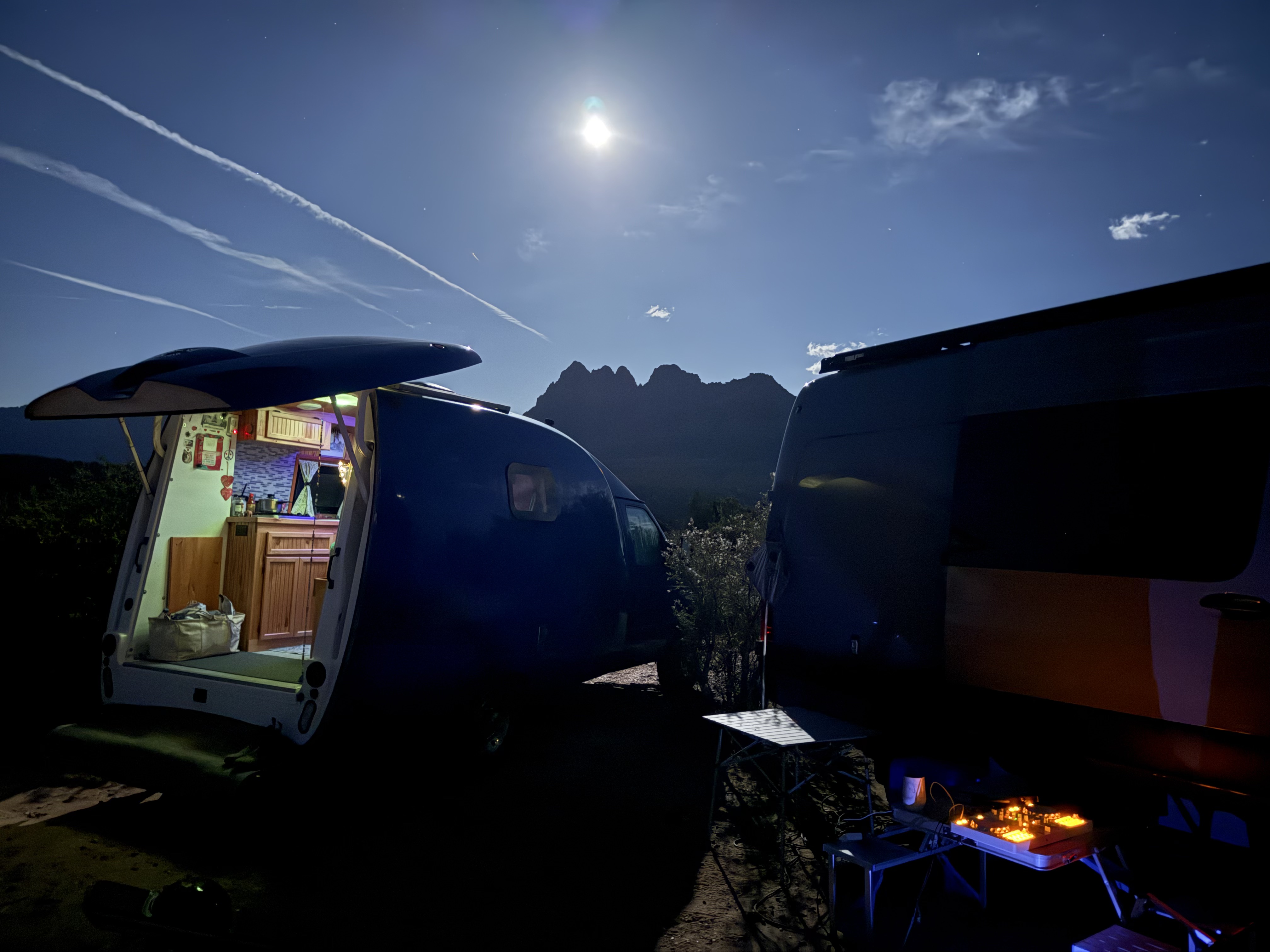 Moonlit camp, Shannon's van open with DJ controller in the foreground, Zion peaks silhouetted behind