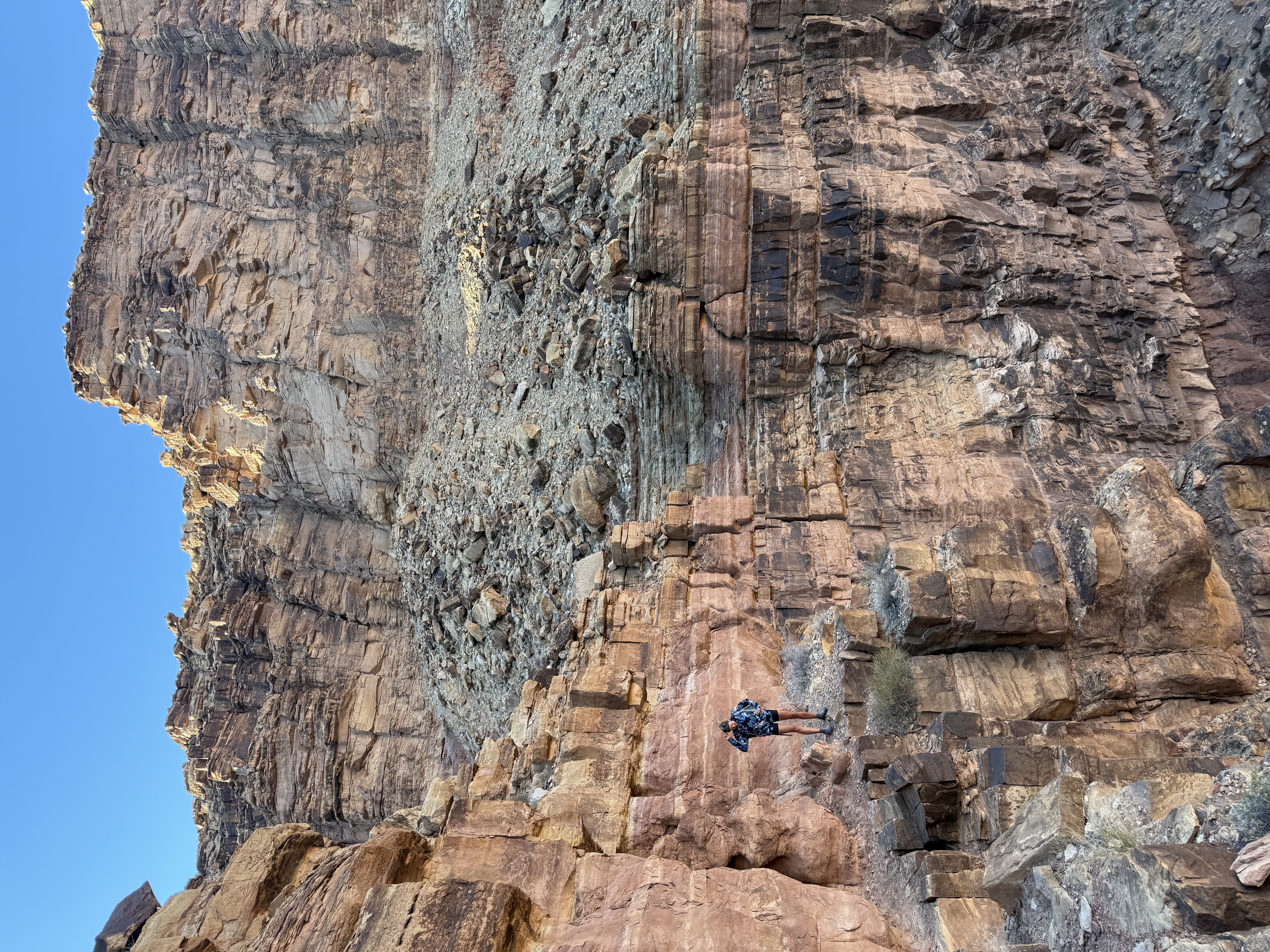 A tiny figure on a ledge beneath a massive canyon wall