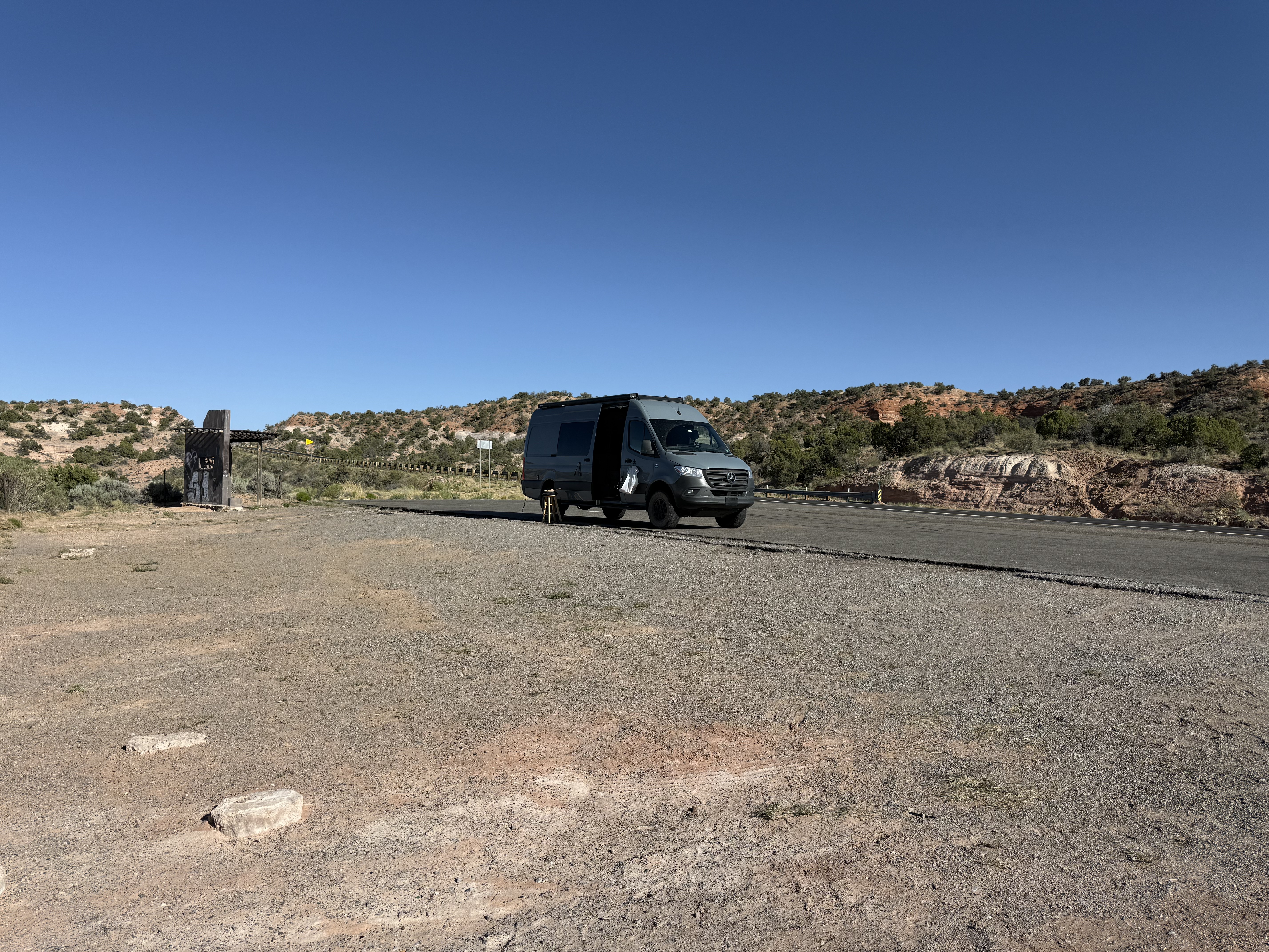 The Sprinter parked at a scenic pulloff past Page, Arizona. Red rock canyon walls and desert scrub under a clear blue sky.