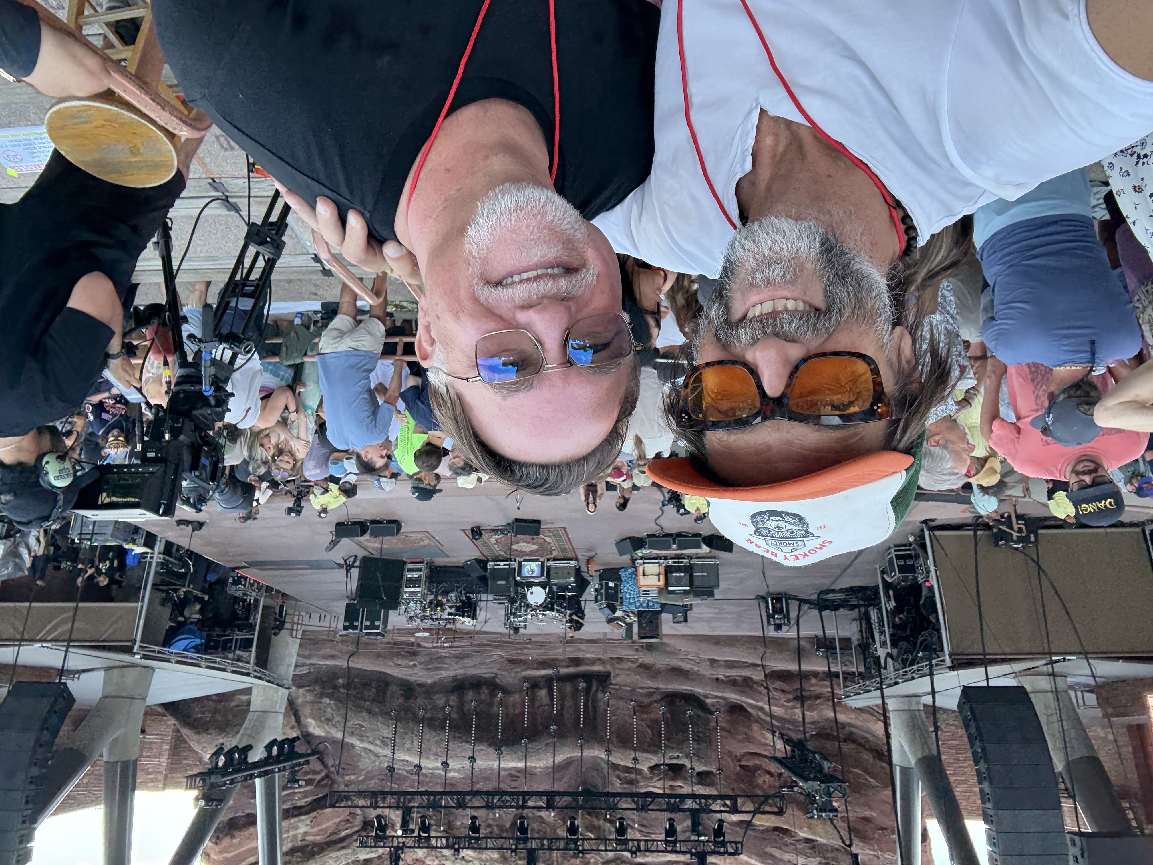Layng and Jeff taking a selfie at Red Rocks Amphitheatre, the stage and iconic red rock formations visible behind them.