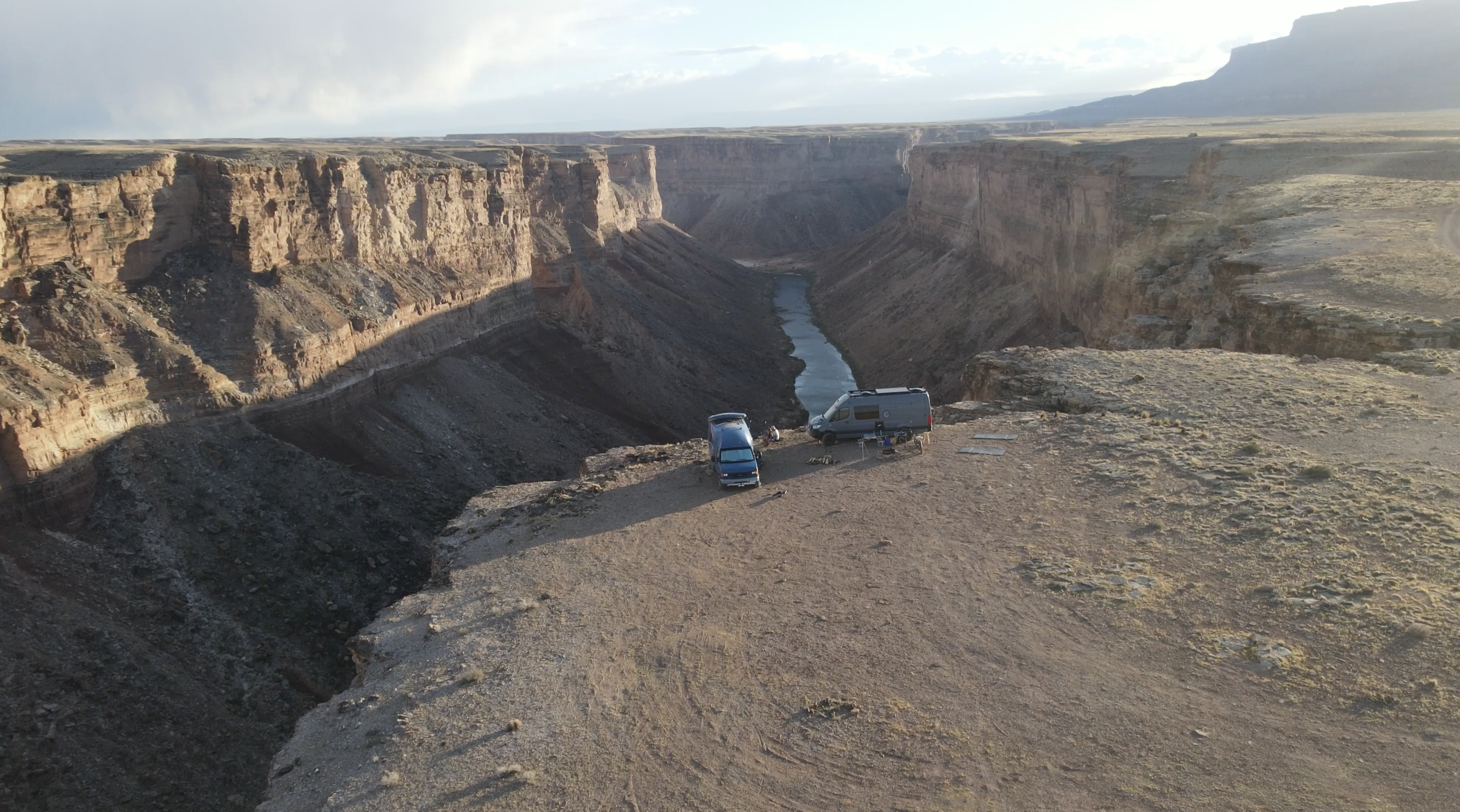Drone shot of two vans parked on the canyon rim, Colorado River far below